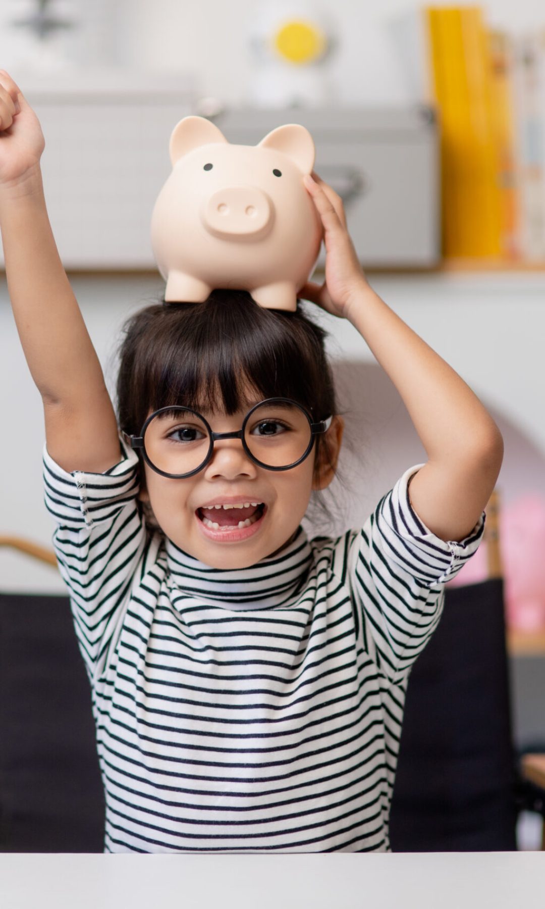 Little Asian girl saving money in a piggy bank, learning about saving, Kid save money for future education. Money, finances, insurance, and people concept